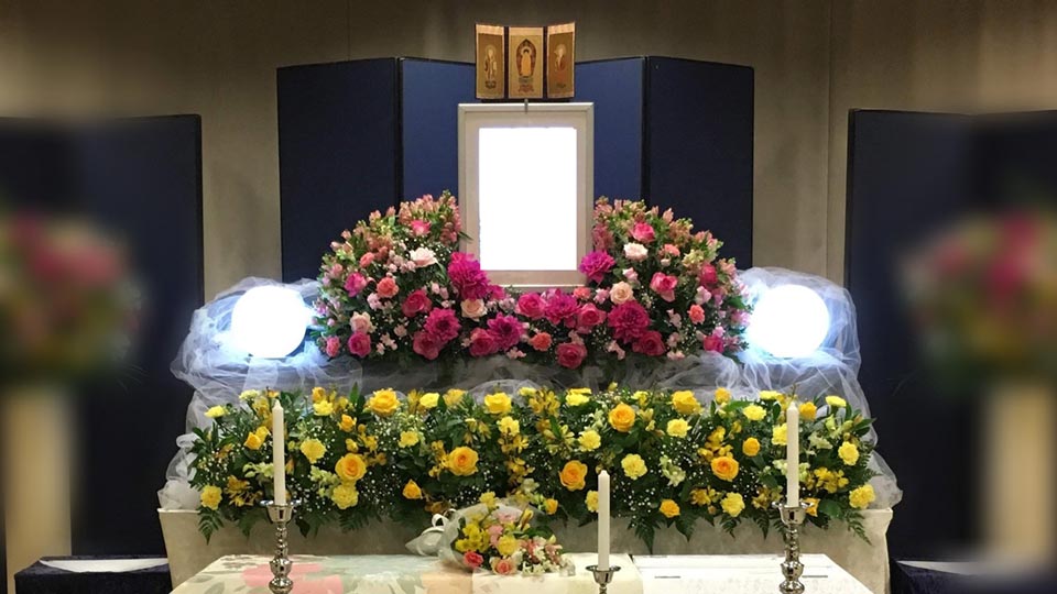 赤、黄を基調とした花が使用されているシンプル家族葬プランの比較的コンパクトな祭壇写真