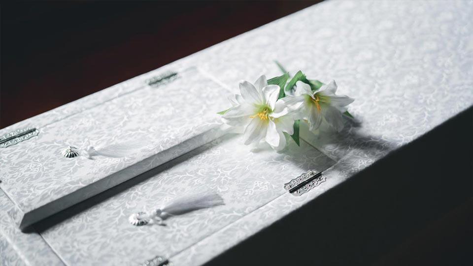 白い棺桶の上に白い花が置かれている、直送プランをイメージした写真