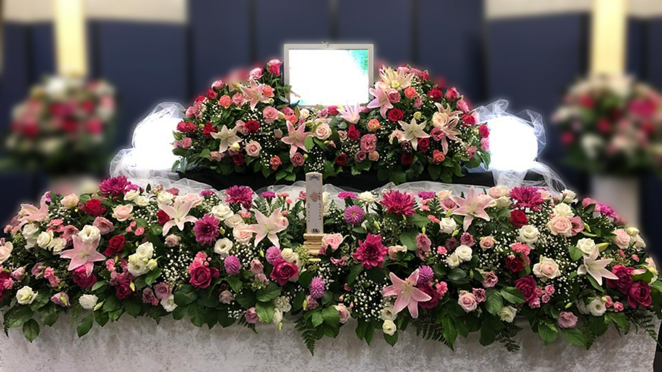 赤、ピンクを基調とした薔薇や百合など様々な花を使用したしっかり家族葬プランの祭壇写真